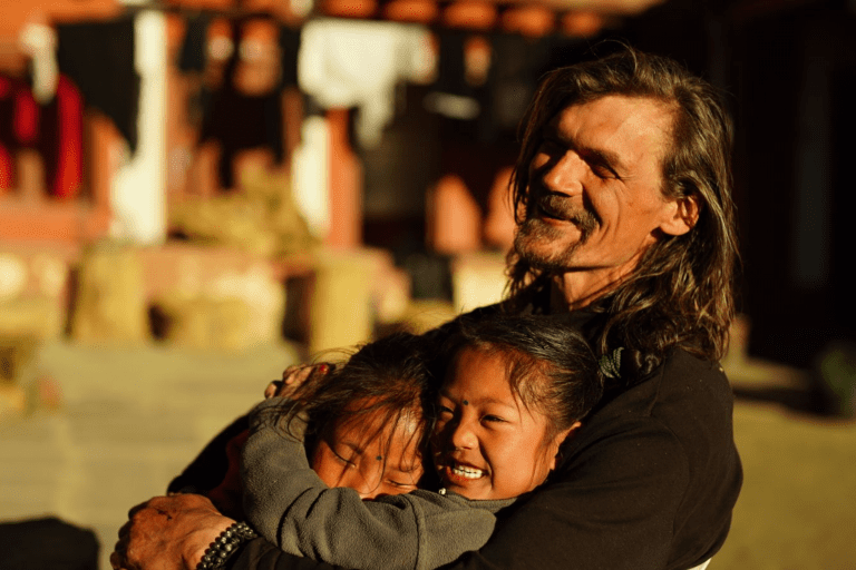 Hombre junto a niñas nepalíes en Muktinath, Nepal, rodeadas de montañas del Himalaya.
